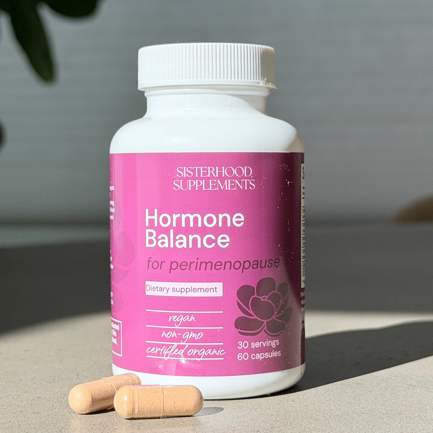 Supplement bottle labeled 'Hormone Balance' by Sisterhood Supplements on a neutral background